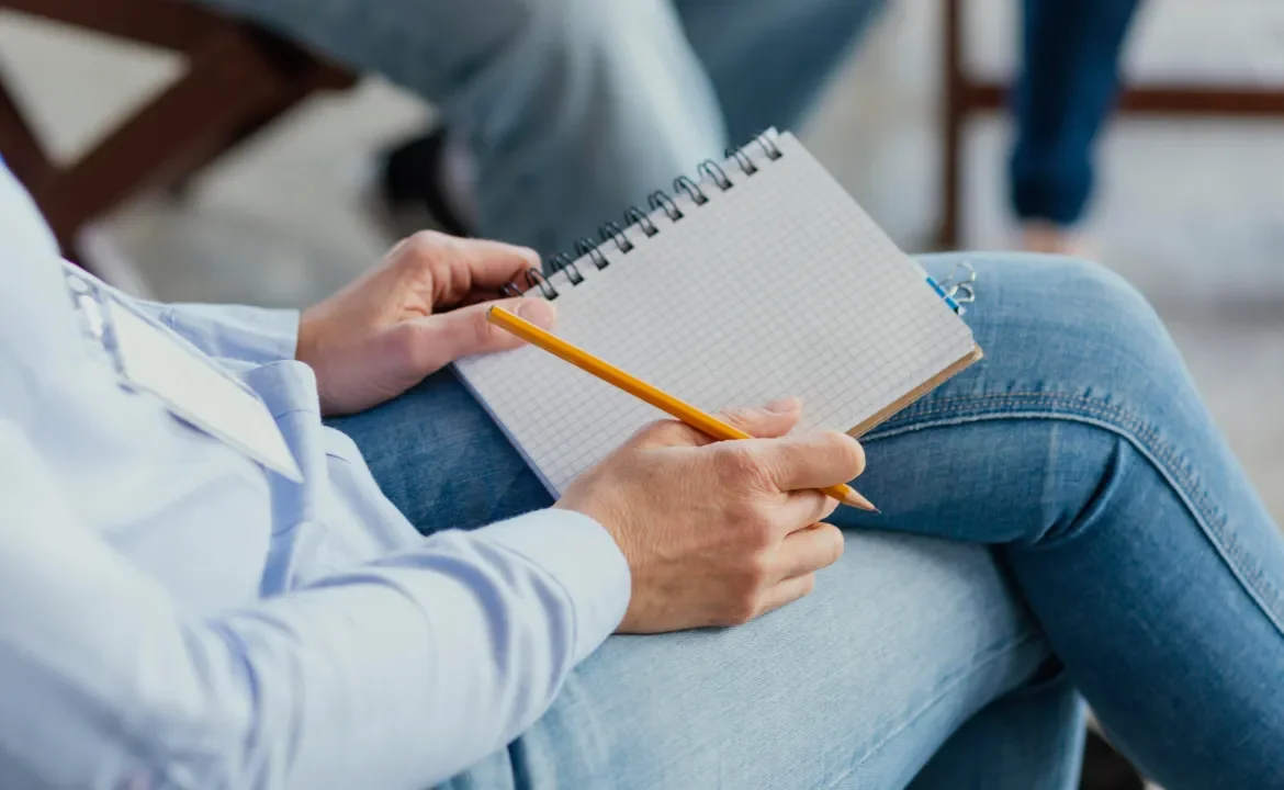 Person holding a notebook and pencil